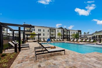 our apartments offer a swimming pool with lounge chairs and tables at The Enclave at Deer Moss Creek, Florida